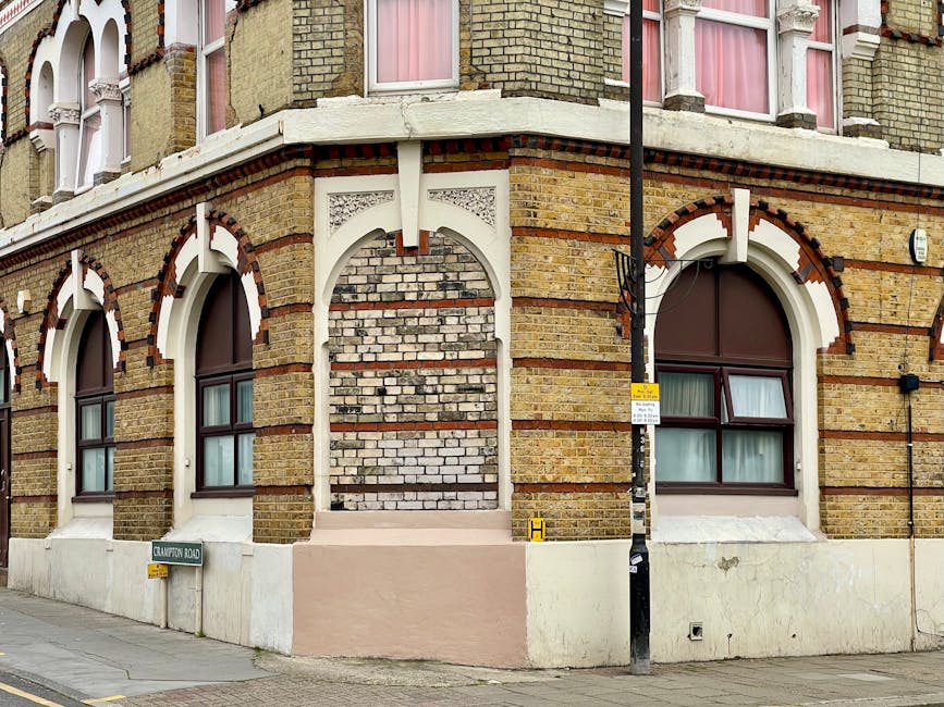 A street scene in Raynes Park featuring a row of elegant Victorian-style white terraced houses with ornate architectural details, bay windows, and decorative mouldings. In the foreground, a large leaf